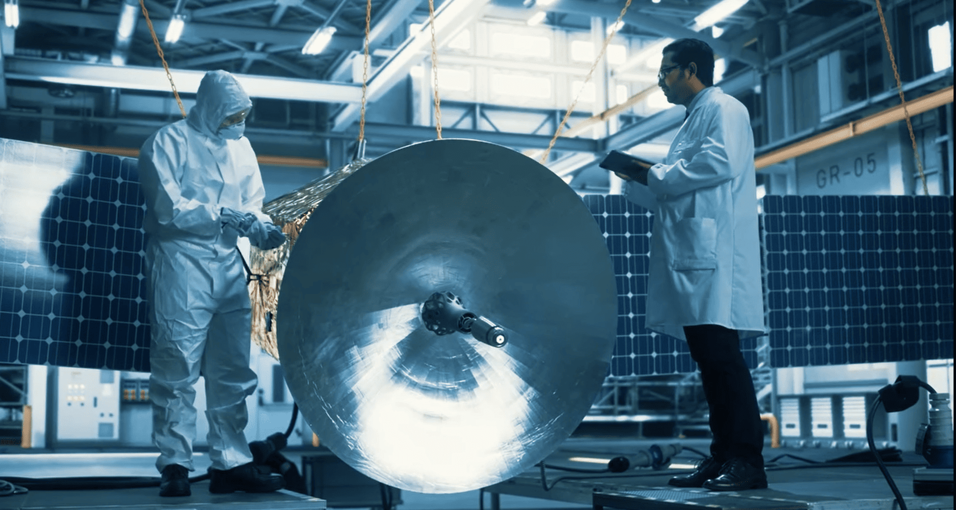 Profesionales inspeccionan un satélite con paneles solares en un laboratorio de I+D+i